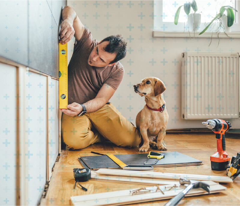 Man measuring the wall with a dog supervising the project
